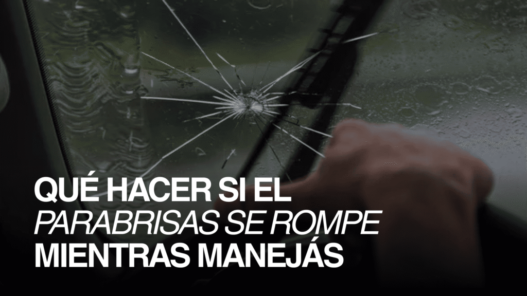 Parabrisas de auto rajado por una piedra bajo la lluvia, con el conductor usando el limpiaparabrisas mientras maneja.